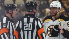 Boston Bruins forward David Pastrnak and NHL referees Brandon Blandina and Mitch Dunning