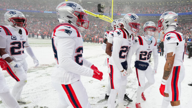 The 2025 Patriots defense celebrates after cornerback Christian Gonzalez's interception vs. the Broncos